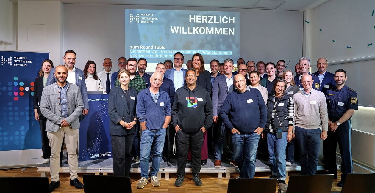 Verschiedene Menschen, Polizistinnen und Polizisten und Journalistinnen und Journalisten stehen auf der Bühne