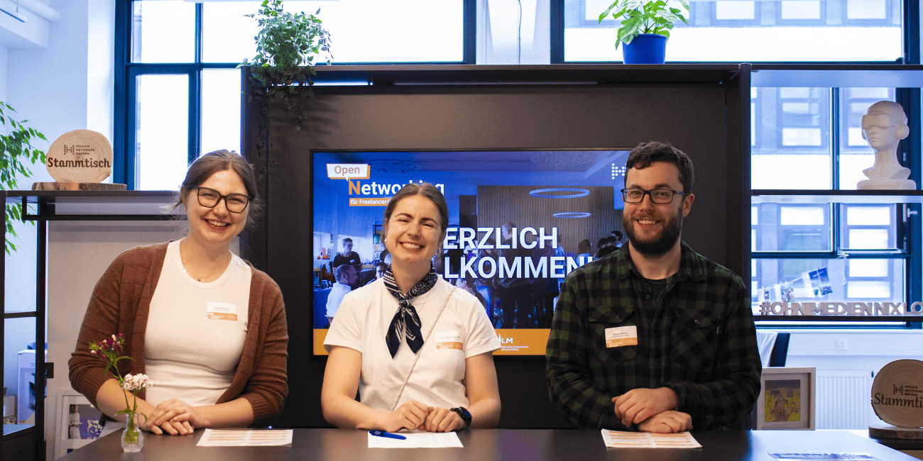 Drei Freelancer bei Medien Bayern begrüßen Gäste im modernen Büro.