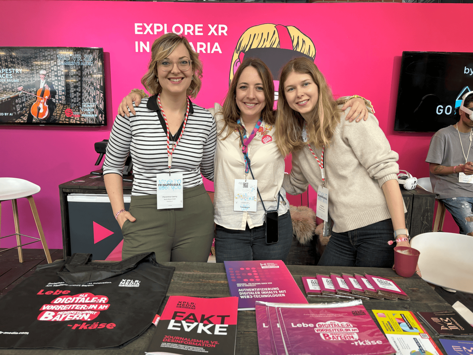 rebublic a xplr Am Messestand von XPLR: Media in Bavaria stehen 3 junge Damen, die sich im Arm halten und lachend in die Kamera schauen