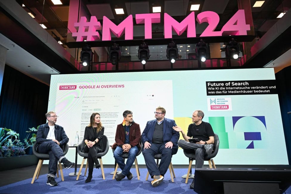 Fünf Personen sitzen auf einer Bühne vor einer großen Leinwand mit der Aufschrift 'Future of Search'. Im Hintergrund ist das Logo '#MTM24' zu sehen. Die Veranstaltung thematisiert KI und deren Einfluss auf die Internetsuche.